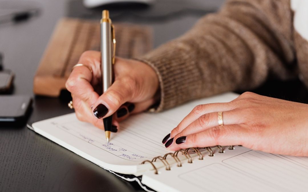 Hands writing in notebook